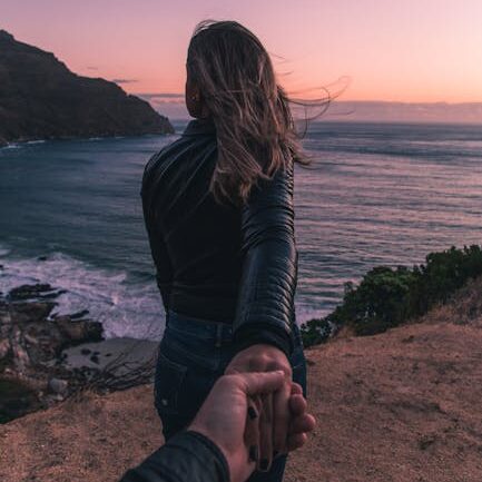 Young couple holding hands by the ocean with a stunning sunset view in Cape Town.