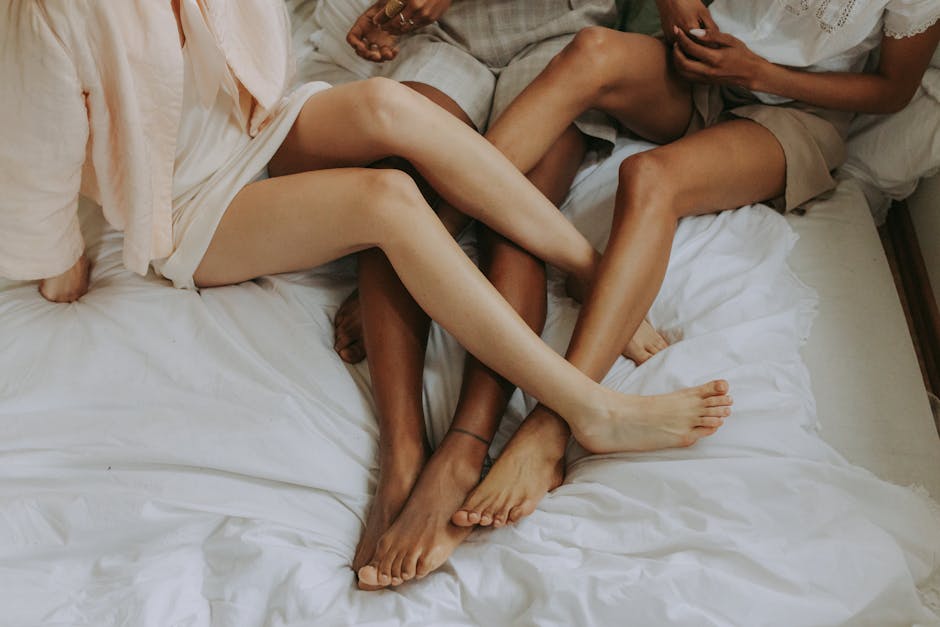 Three women lounging and embracing on a bed, symbolizing connection.