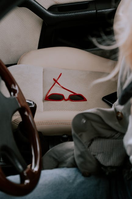 Close-up of stylish red sunglasses on a car seat, suggesting a casual road trip vibe.